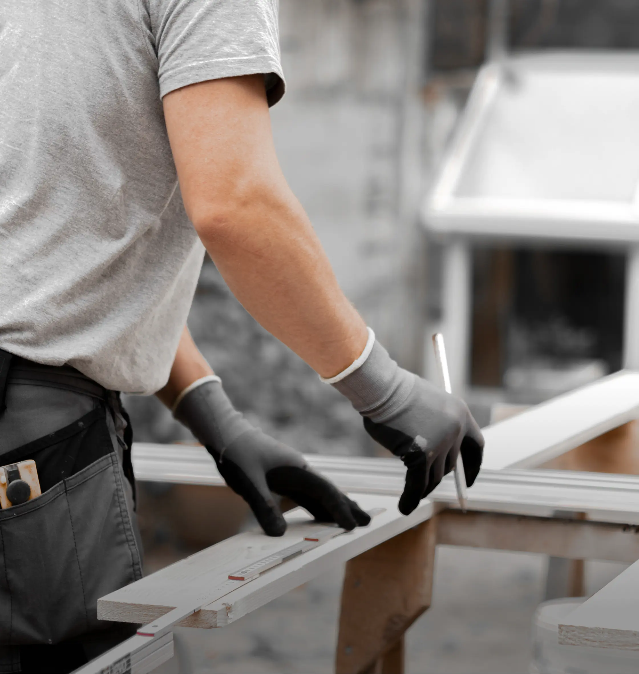 Contractor in work gloves measuring a wooden board