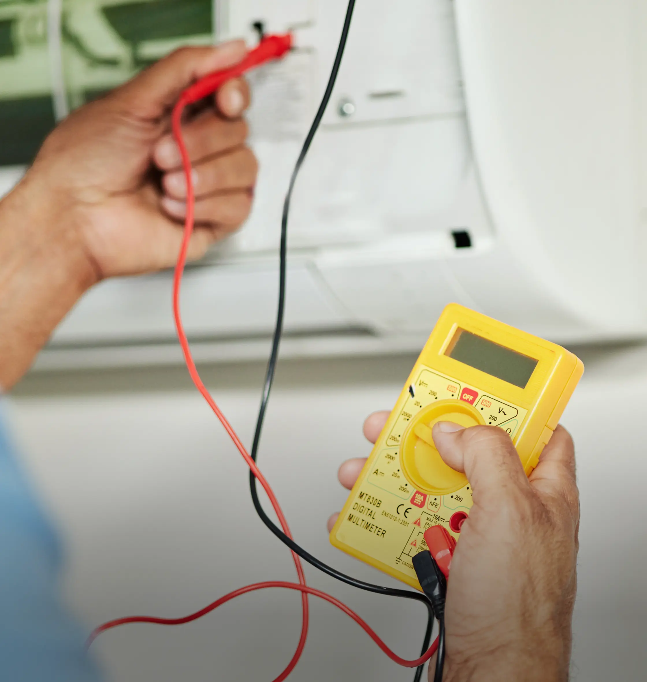 HVAC technician testing an air conditioner with a multimeter