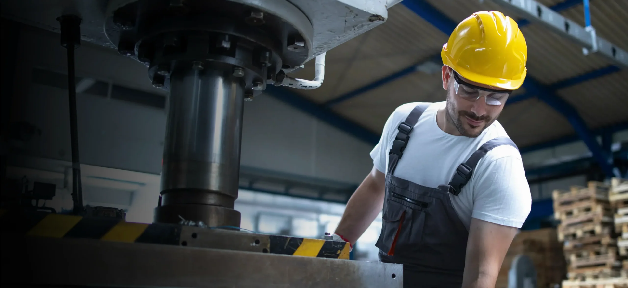 Machine operator in a hard hat working at an industrial press