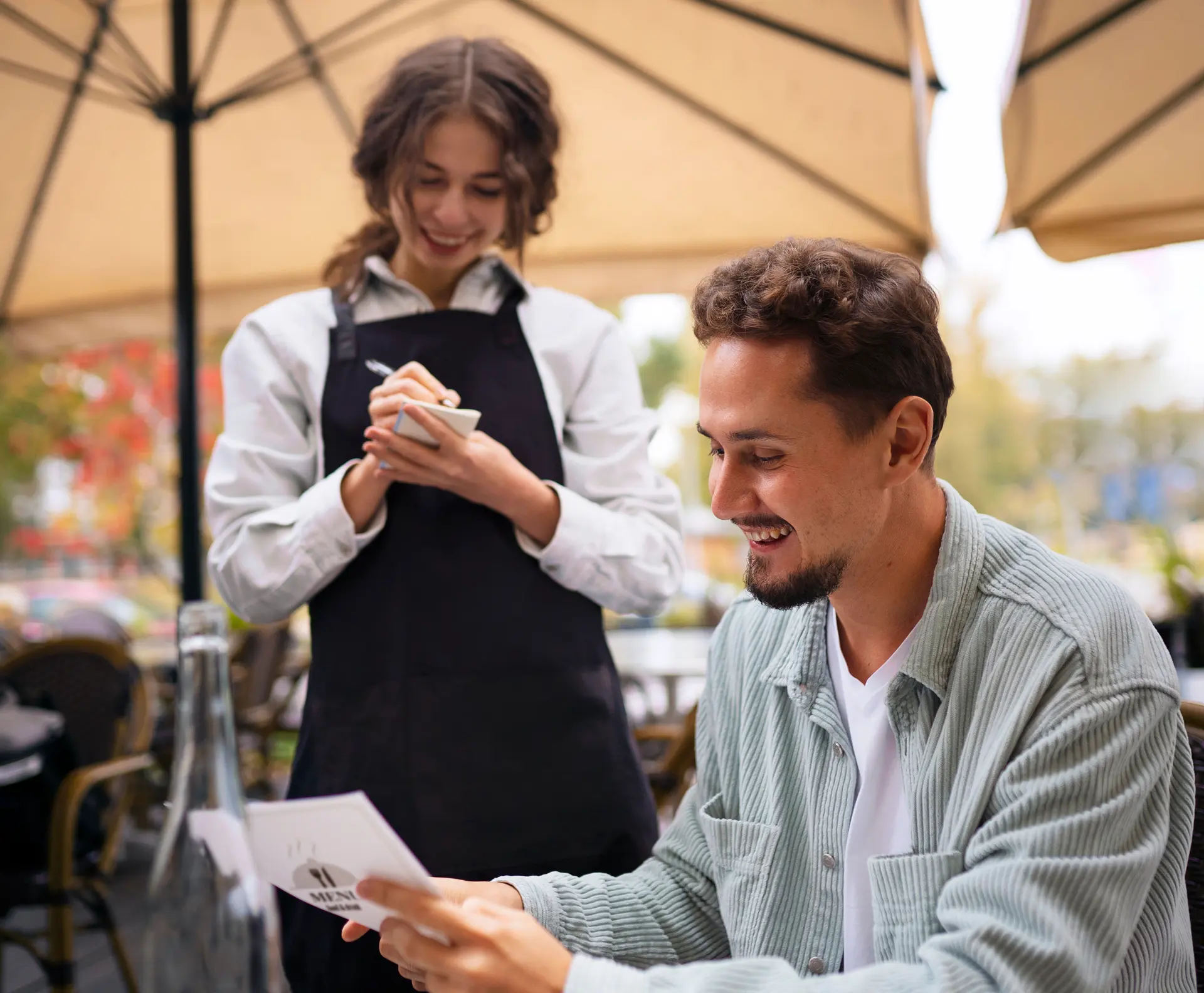 Smiling server taking a customer’s order at an outdoor restaurant patio