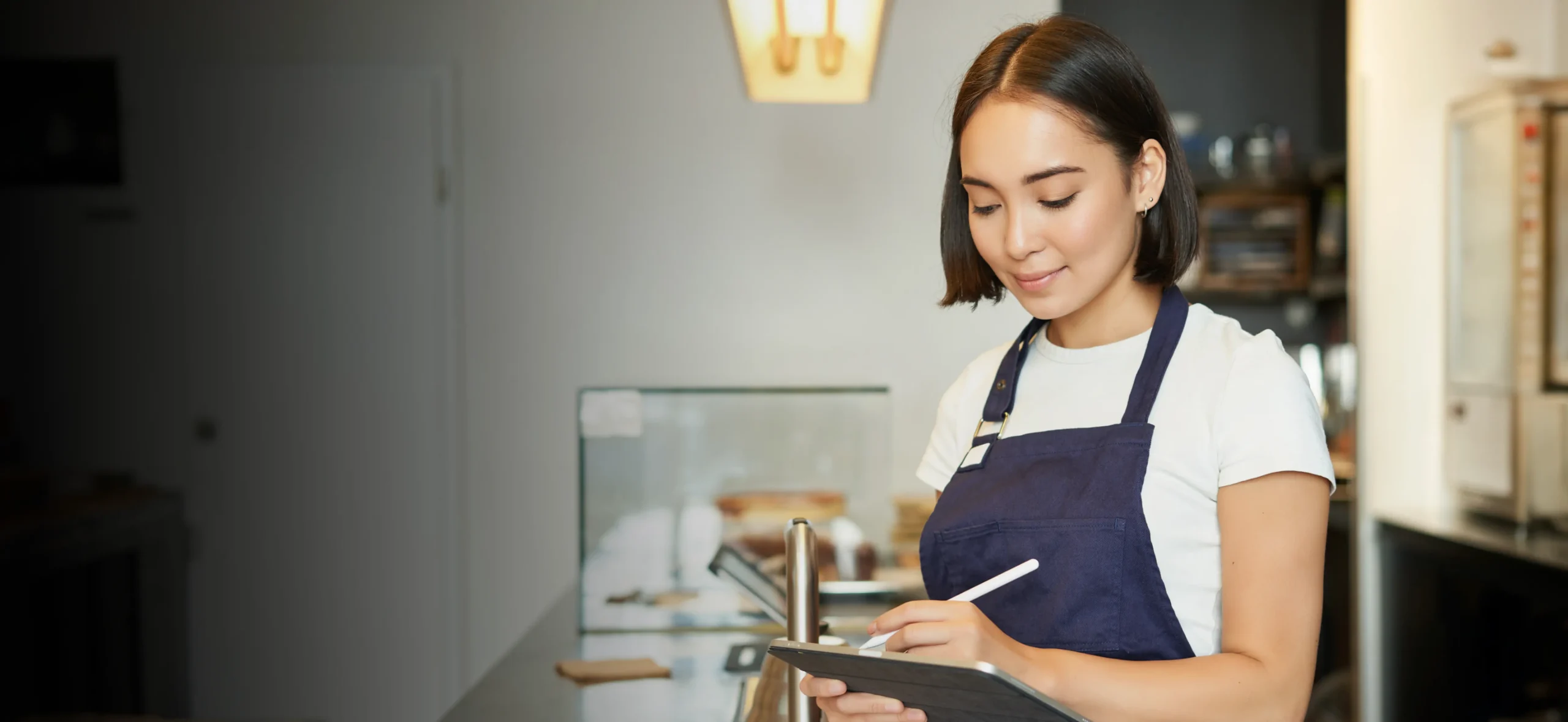 Restaurant worker taking notes on a tablet behind the counter