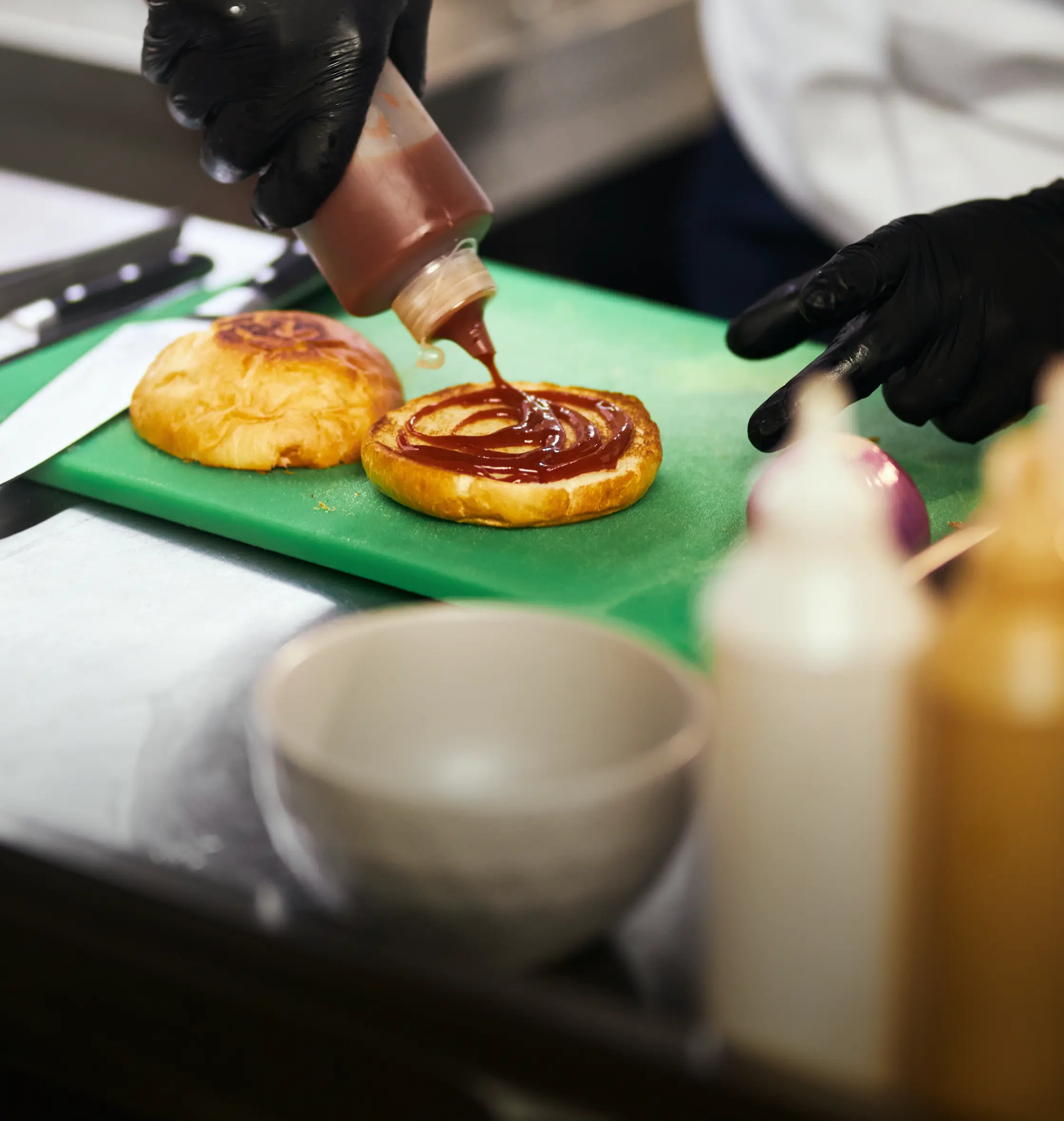 Cook adding sauce to burger buns in a food truck kitchen