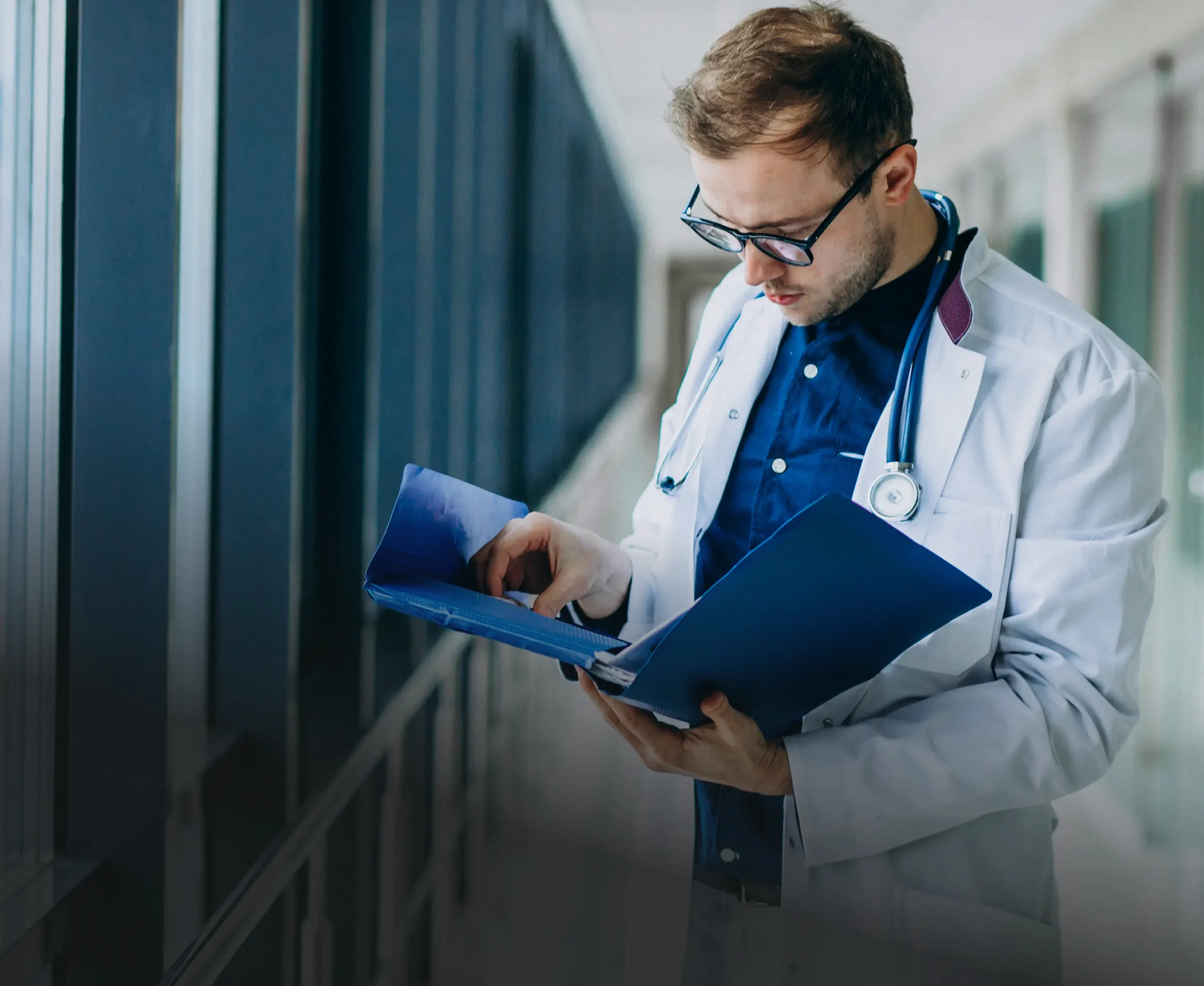 Doctor reviewing a patient file in a clinic hallway