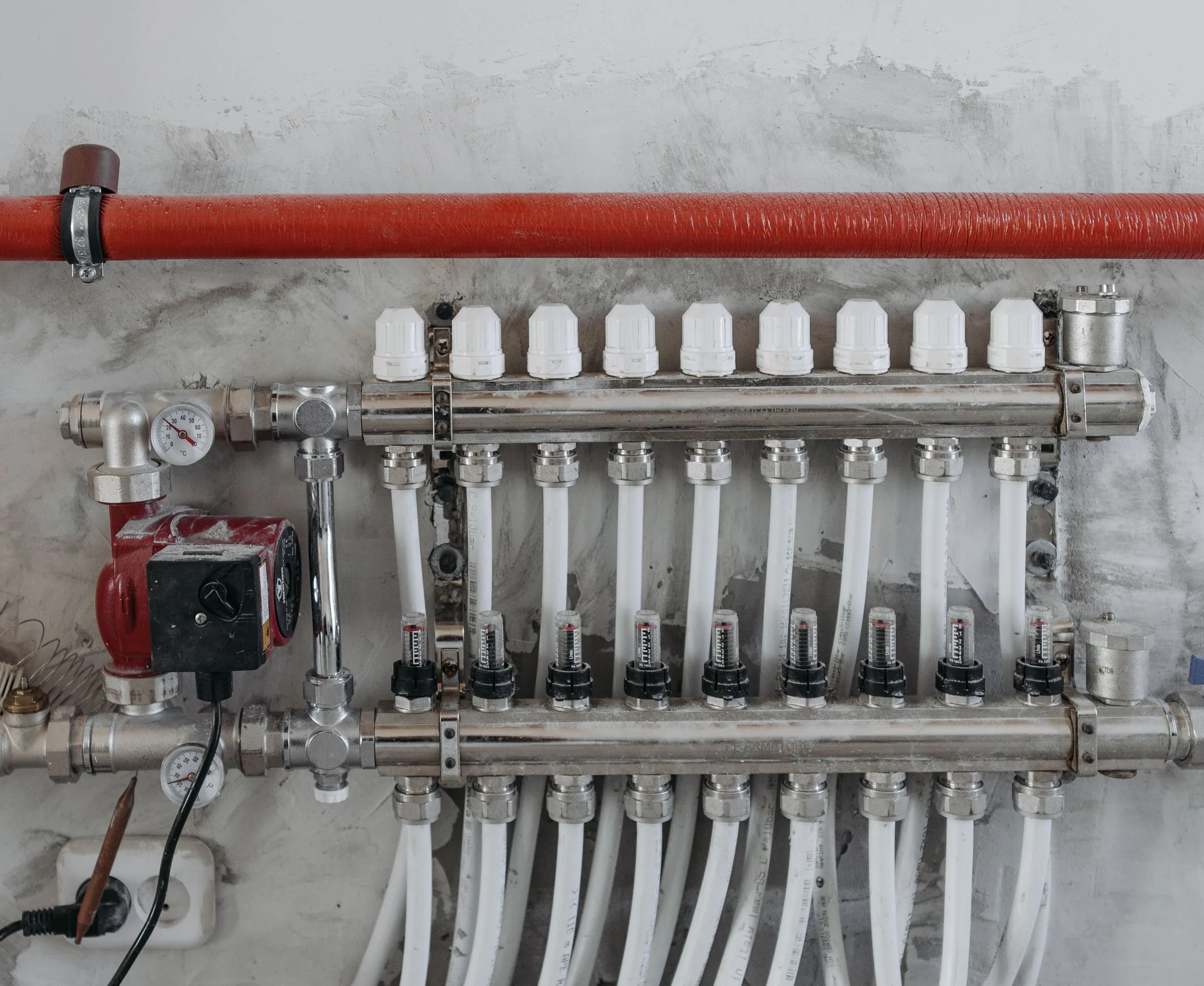 Plumbing manifold with supply lines on a bare wall during rough-in