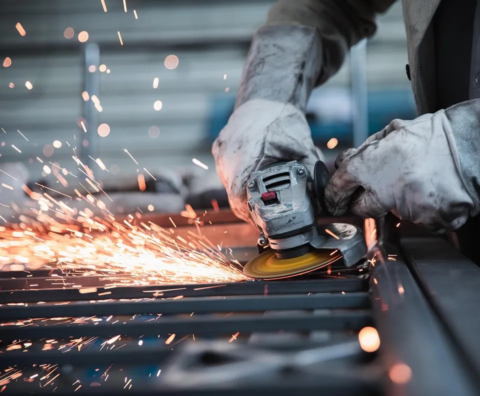 Worker grinding steel with sparks flying
