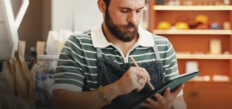 Retail shop owner in an apron working on a tablet