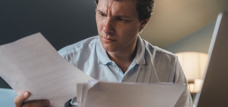 Small business owner reading a letter from a lender at his desk