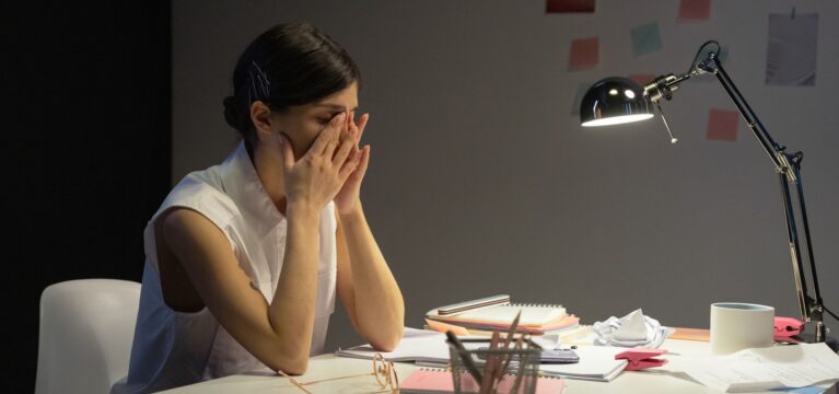 Small business owner rubbing her eyes at her desk after a long day of decisions