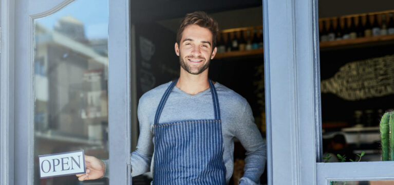 Bearded smiling man with "Open" sign