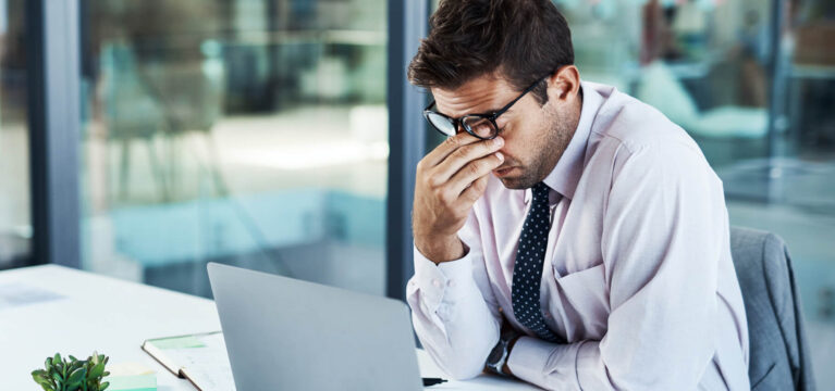 Shot of a businessman looking stressed while sitting at his desk