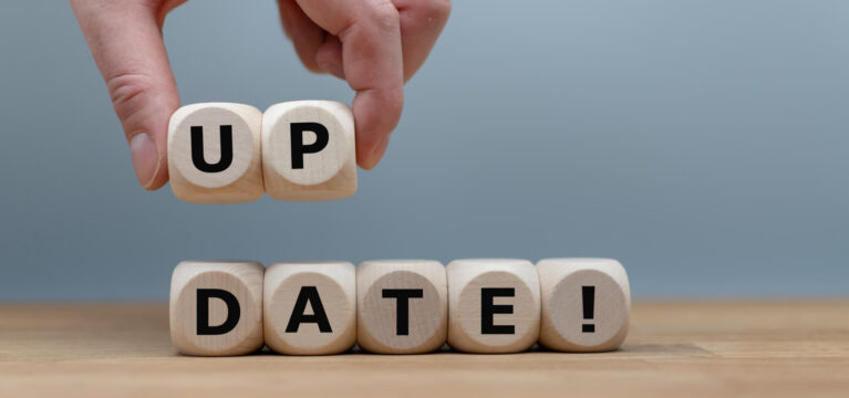 Dice form the word "UPDATE!" while a hand rises the letters "UP"