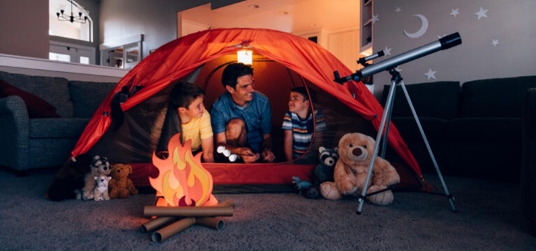Happy father and his sons camping indoors