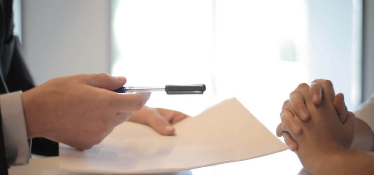 Potential business-owner getting pen and paper to sign loan application documents
