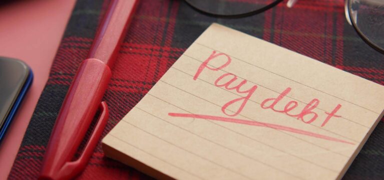 Sticky note with "Pay debt" reminding note