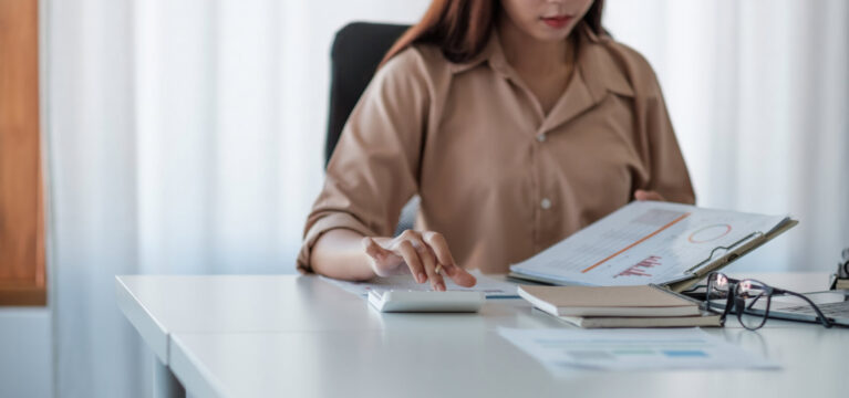 Business woman working in finance and accounting Analyze financial budget with calculator and paperwork in the office