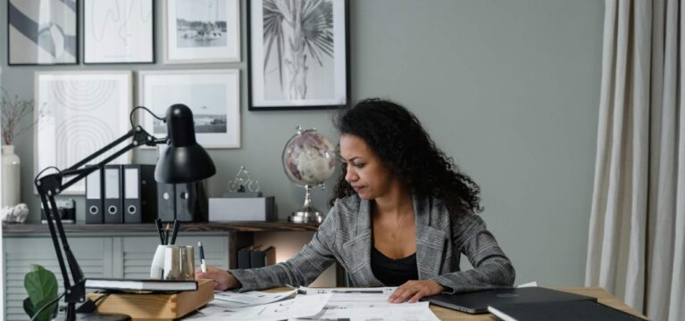 Business professionals reviewing financial documents and budget spreadsheets at a desk with a laptop and calculator.